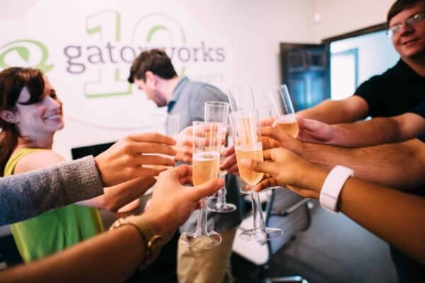 In an office setting buzzing with energy, people clink champagne glasses, celebrating another successful year at Baton Rouge Radio Station. The team, part of Guaranty Broadcasting's vibrant community, toasts to future achievements and cherished memories.