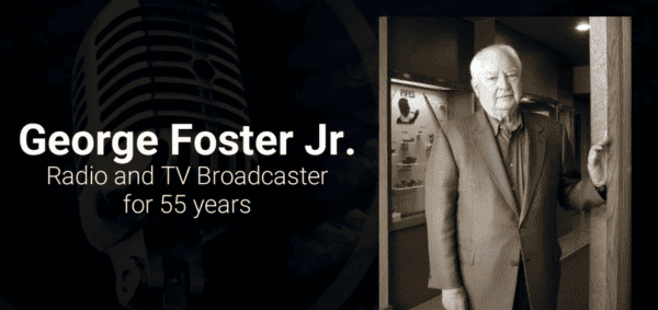 Black and white image of a man in a suit standing near a display case. Microphone graphic and text: 